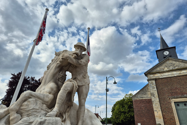 Statue of a man on horseback, holding a flag, with a scenic background enhancing the historical significance.