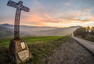 A roadside cross in the mountains of Monte Sole Park, representing a place of remembrance amidst the scenic landscape.