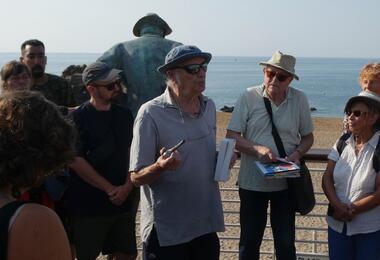 A group of diverse individuals gathered around a large statue, engaging in conversation and taking photos.