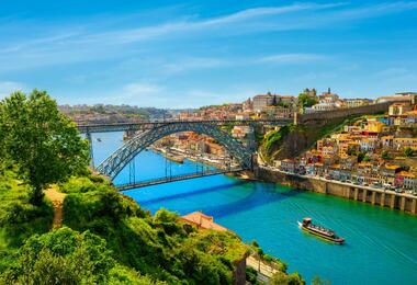A scenic view of Porto, Portugal, showcasing its historic architecture and the Douro River under a clear blue sky.