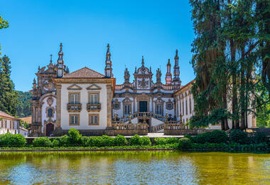 A large building stands prominently with a serene pond in front, reflecting its architecture.