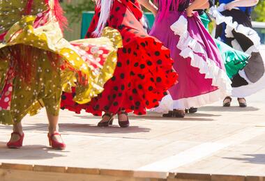 A group of women performing flamenco dance, wearing colorful dresses and showcasing traditional movements.