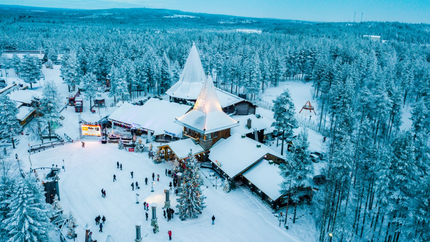 A panoramic view of a snowy ski resort, featuring slopes, pine trees, and cosy lodges under a clear blue sky.