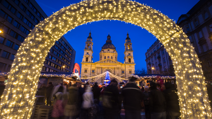 A large illuminated arch with a crowd of people gathered in front, creating a festive atmosphere.