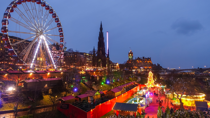 Festive Edinburgh Christmas market with colourful stalls, twinkling lights, and visitors enjoying seasonal treats and activities.