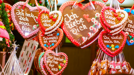 Gingerbread hearts decorated with icing, hanging from a string, creating a festive display.