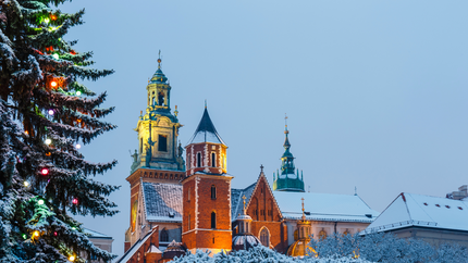 A brightly lit Christmas tree stands in front of a church, creating a festive holiday atmosphere.