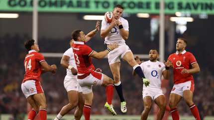England player tackles a Welsh player during a rugby match, showcasing athleticism and competitive spirit.