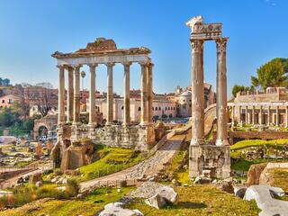 The Roman Forum in Rome, Italy, showcasing ancient ruins and columns under a clear blue sky.