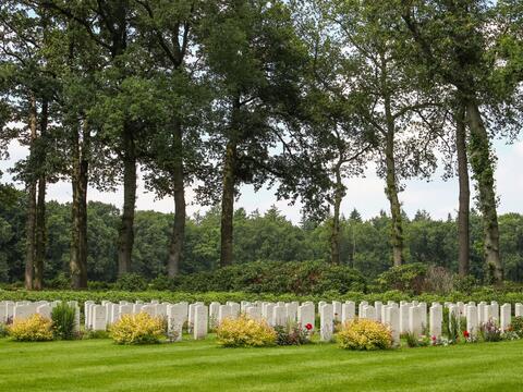 Gravestones in an airborne war cemetery, adorned with a vibrant row of white and yellow flowers.