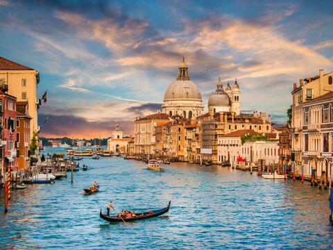 The Grand Canal in Venice, Italy, showcasing historic buildings and gondolas on the water under a clear blue sky.