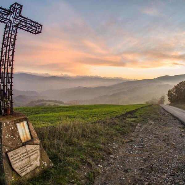 A roadside cross in the mountains of Monte Sole Park, representing a place of remembrance amidst the scenic landscape.