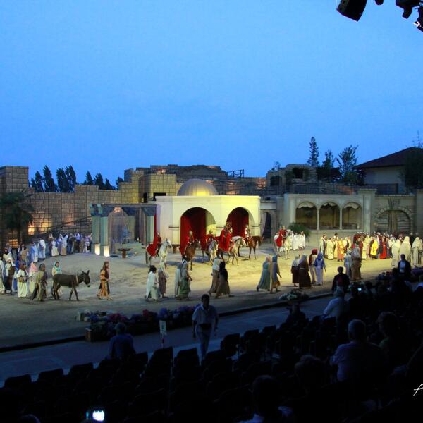 Actors in elaborate costumes perform on stage during the Sordevolo Passion Play, with horses included in the scene.