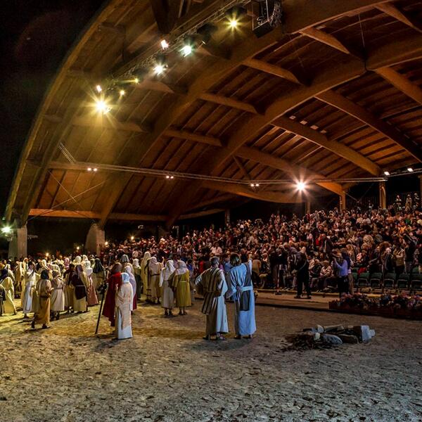 A large crowd gathers on the sand, watching the Sordevolo Passion Play performance.