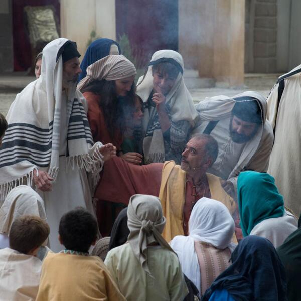 A group in traditional clothing surrounds a man, engaged in a dramatic scene from the Sordevolo Passion Play.