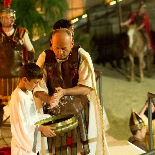 A scene from the Sordevolo Passion Play shows a man in costume washing his hands from a bowl held by a child.