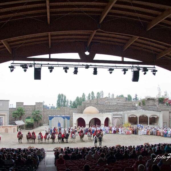 A large crowd gathers in front of a stage during the Sordevolo Passion Play, showcasing an engaged audience.