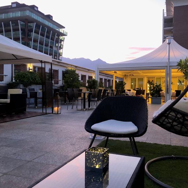 Roof garden at Hotel Agora Palace in Biella, featuring chairs and tables set for guests to enjoy the ambiance.