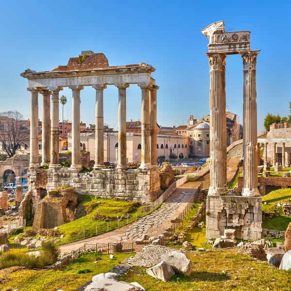 The Roman Forum in Rome, Italy, showcasing ancient ruins and columns under a clear blue sky.