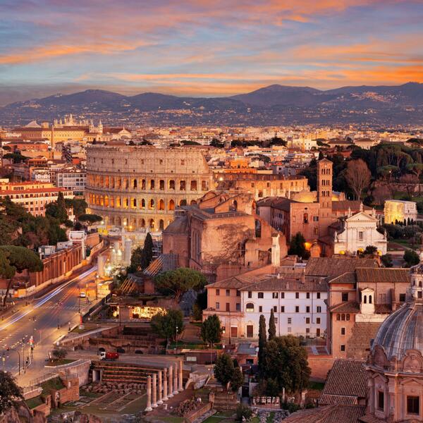 Sunset over Rome, showcasing the silhouette of historic buildings and the warm glow of the sky.