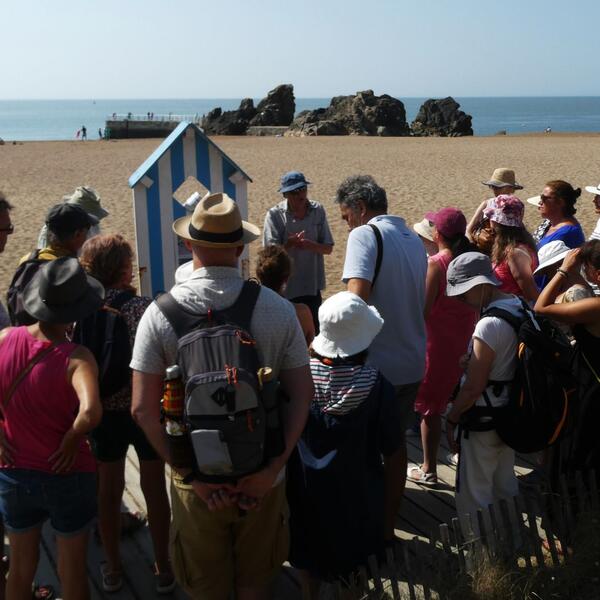 Several individuals gather on the beach, with waves and sand in the background.