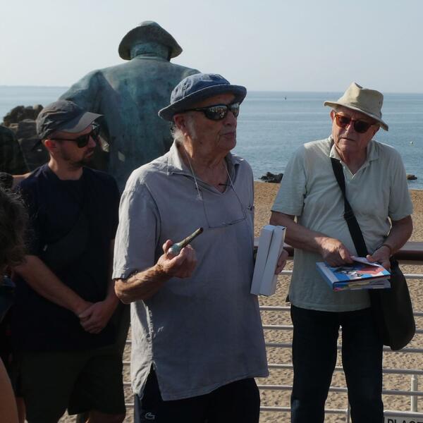 A group of diverse individuals gathered around a large statue, engaging in conversation and taking photos.