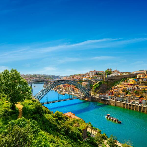 A scenic view of Porto, Portugal, showcasing its historic architecture and the Douro River under a clear blue sky.