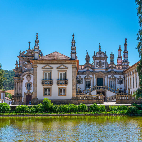 A large building stands prominently with a serene pond in front, reflecting its architecture.