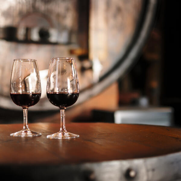 Two elegant wine glasses filled with port wine, placed on a wooden table.