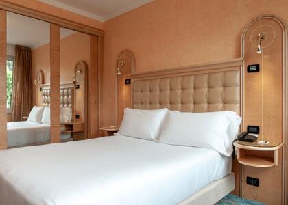 Interior of Hotel Agora Palace showing a cozy bed and a stylish mirror on the wall.